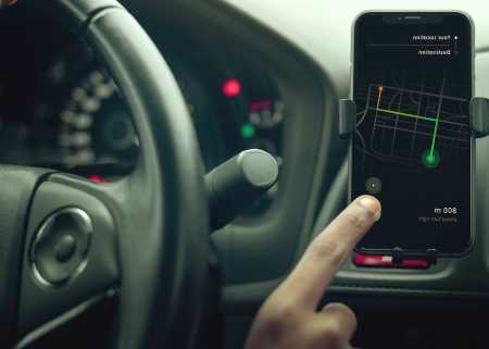 Hand going to touch the phone screen to use driving apps 