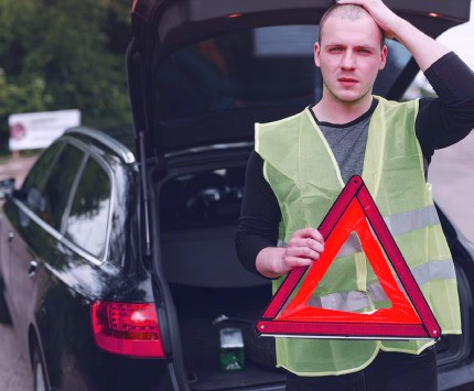 A man holds road triangle which is part of a crucial car tools 