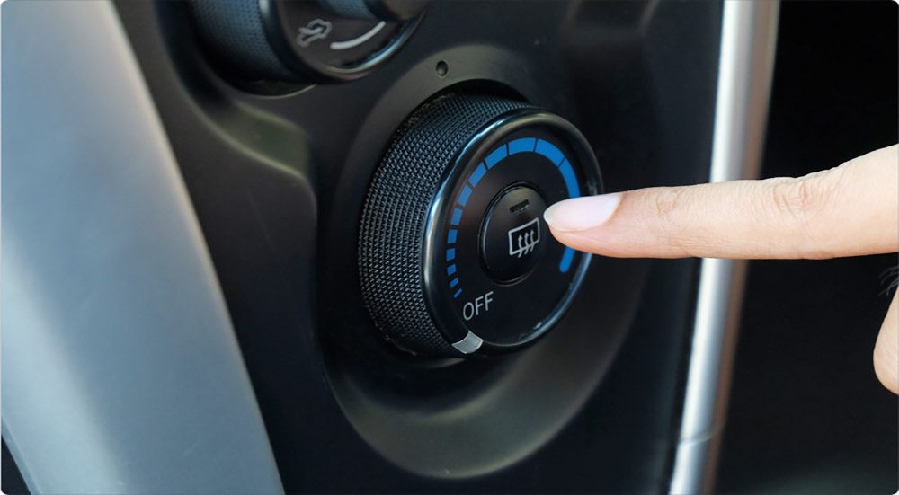 Pressing a button to heat the windows of a car