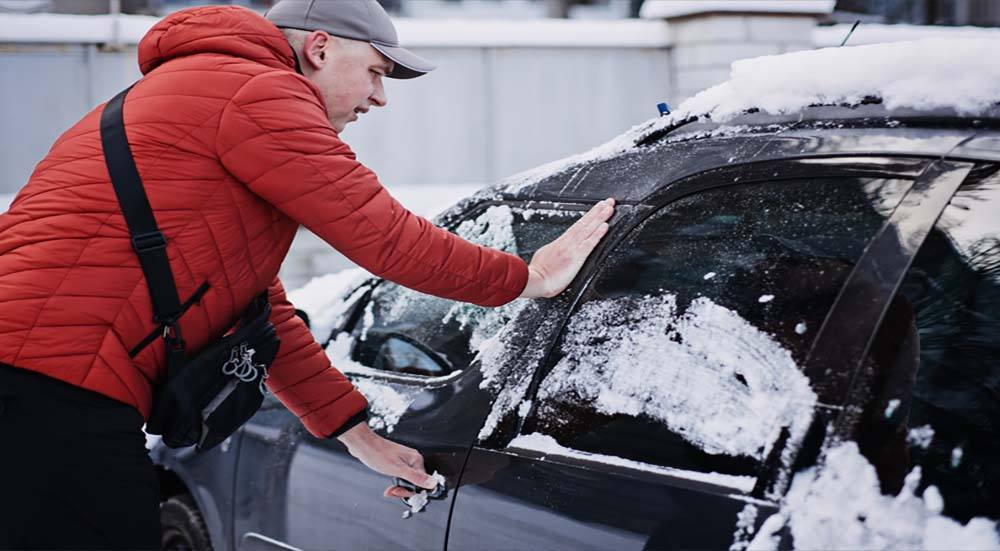 A man opens his car door after defrosting the windows